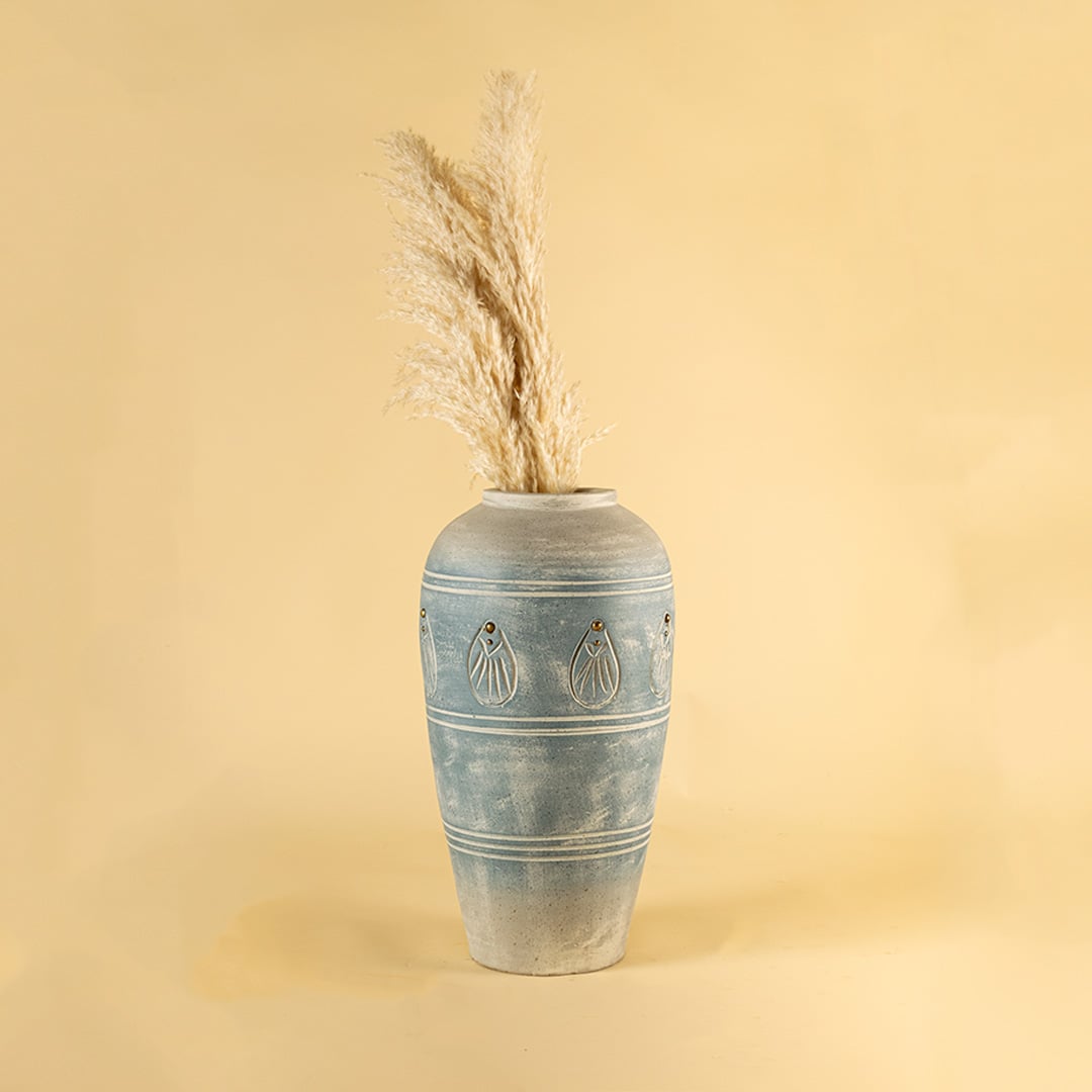 Tall blue carved terracotta vase styled in a warm interior adding handcrafted charm and elegant detailing to modern natural home decor styling.