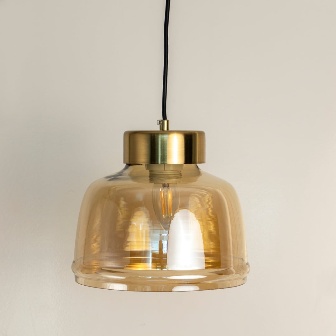 Amber glass pendant light featuring clear textured glass shade and brass metal holder displayed with lights off.