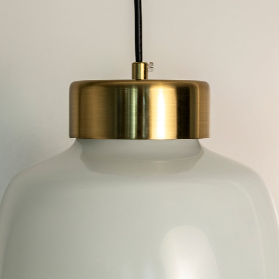 Closeup of frosted glass pendant lamp emitting soft warm light through matte glass shade with golden top detail.