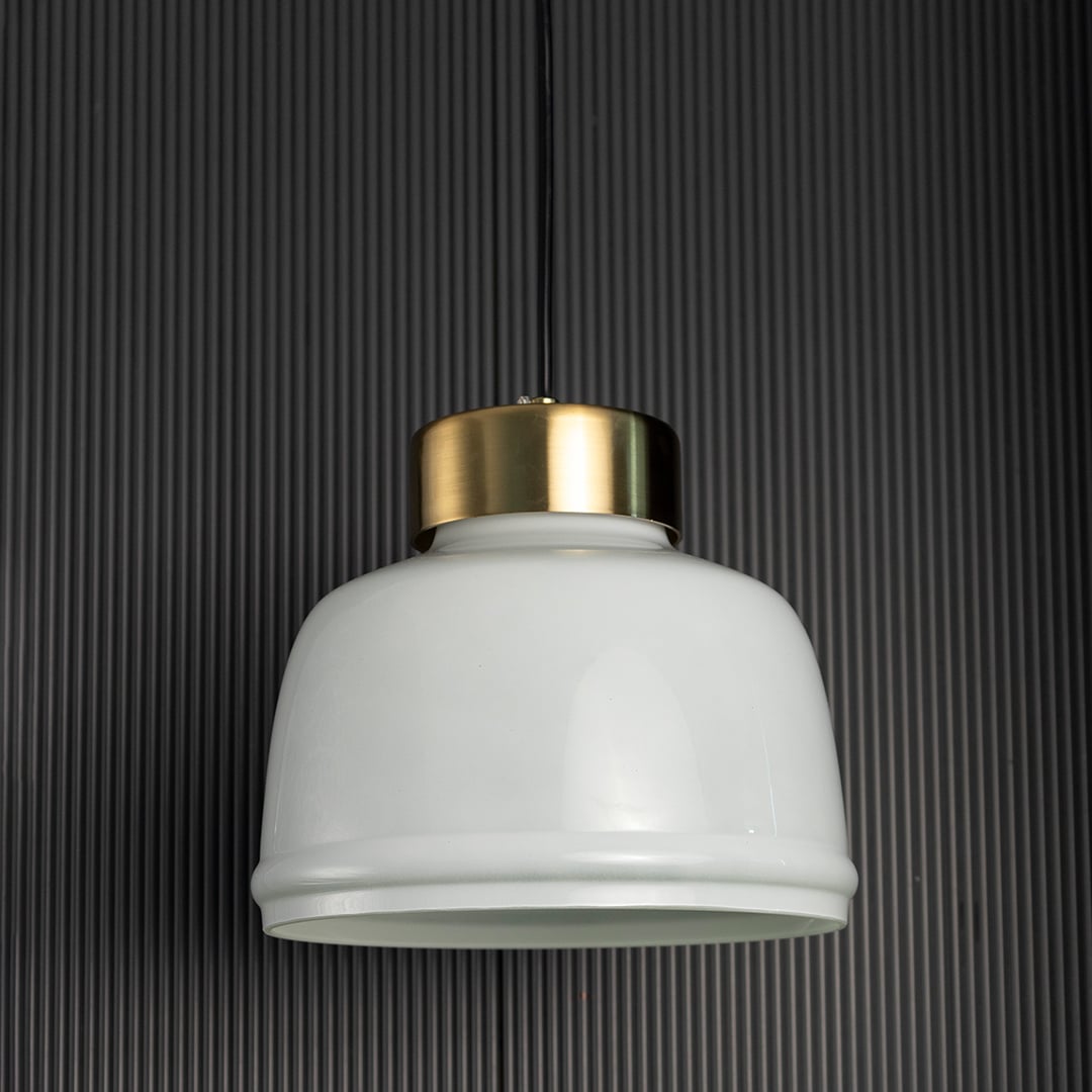 Frosted glass pendant light turned off with minimal white shade and brushed gold top displayed against black background.