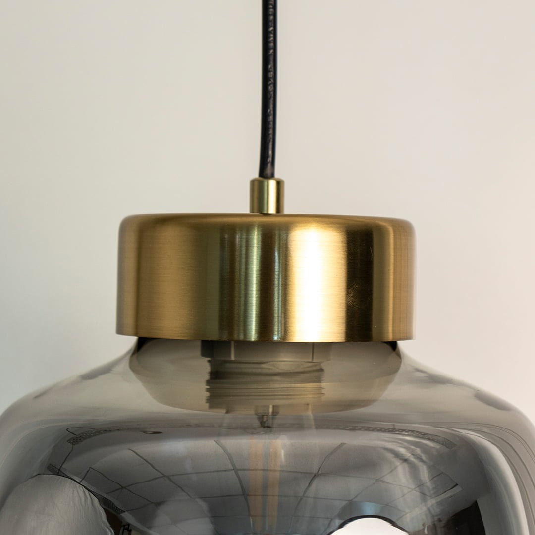 Smoked glass pendant lamp illuminated softly with golden glow turned off highlighting its tinted shade and modern metal detailing.