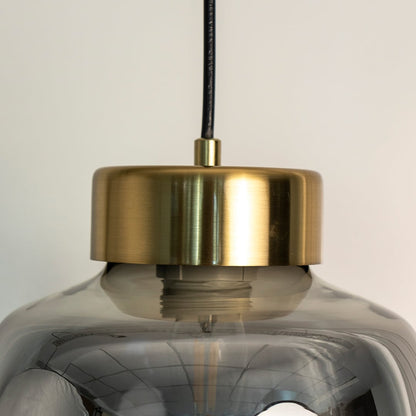 Smoked glass pendant lamp illuminated softly with golden glow turned off highlighting its tinted shade and modern metal detailing.