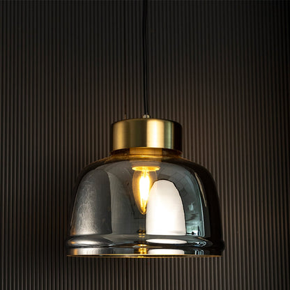 Smoked glass pendant light glowing through golden tinted shade creating a modern luxurious appeal on dark background.