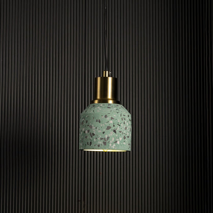 Grey terrazzo pendant light turned on with brass accent creating warm modern glow against black background.