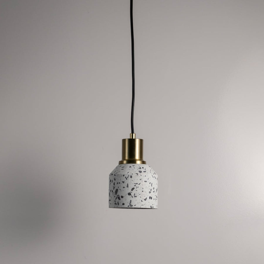 Minimal terrazzo pendant light with brass finish and black cord against white wall perfect for modern interiors.