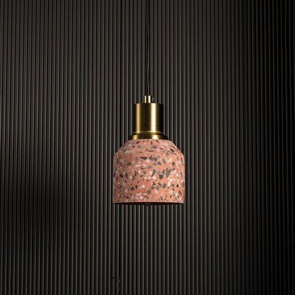 Pink terrazzo pendant light with brass accent against black background for contemporary industrial interiors.