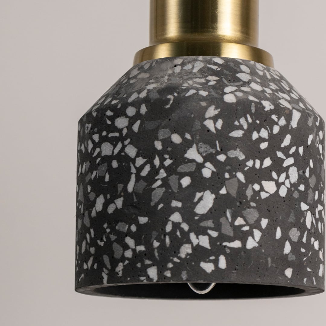 Modern black terrazzo pendant light featuring a smooth speckled texture and metallic brass top displayed against a neutral background.