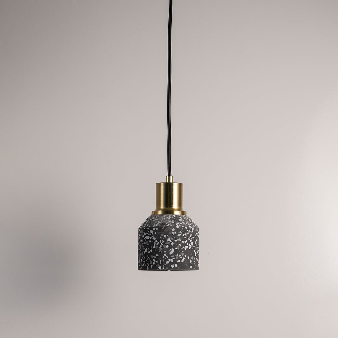 Black terrazzo pendant lamp with golden accent  turned off against a white background for a sophisticated industrial look.