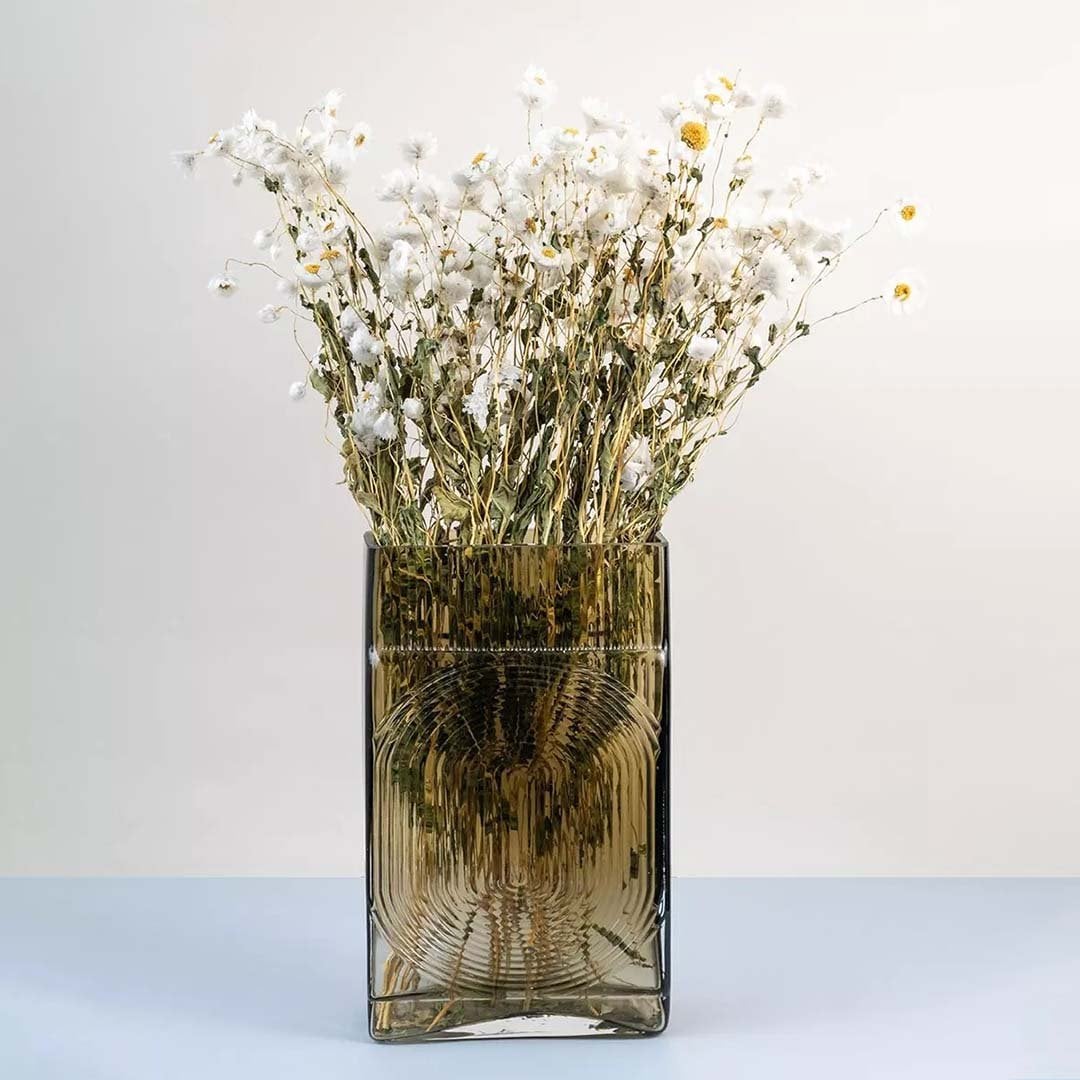 Dried white daisy flowers arranged in a transparent brown glass vase adding a rustic and elegant touch to home decor.