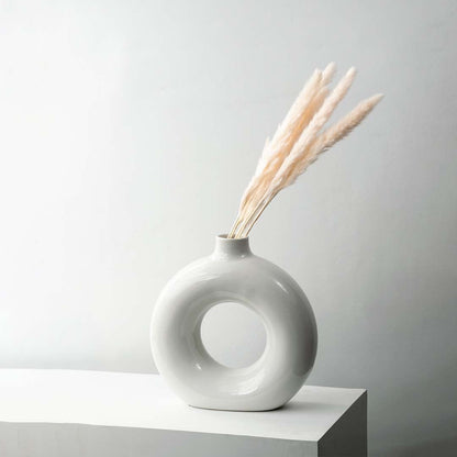 Beige pampas grass stems arranged in elegant vase dried natural fluffy floral bunch on white background.