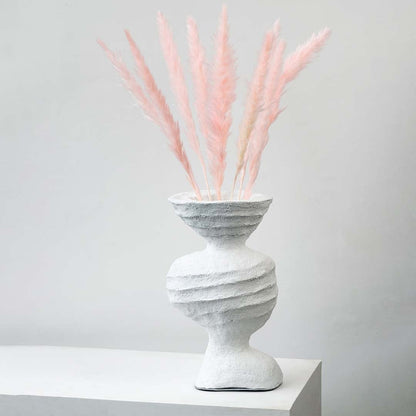 Light pink pampas grass stems styled in textured white ceramic vase elegant boho home decor on white backdrop