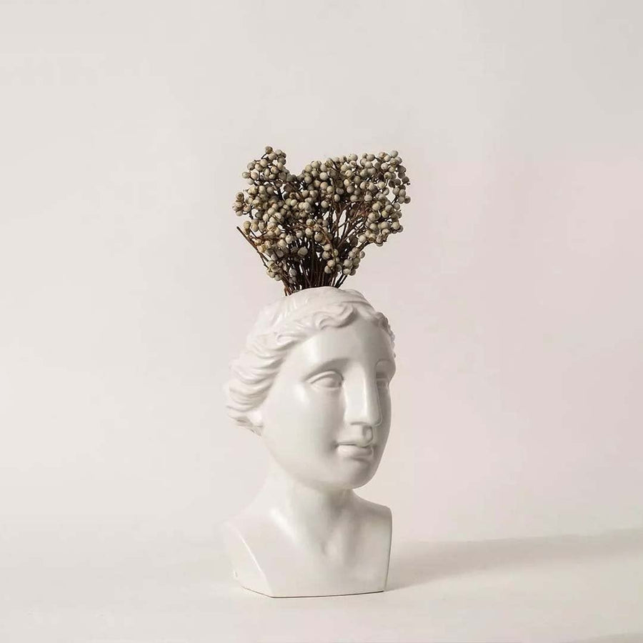 Natural dried white berry stems arranged in a modern white sculpture vase on a soft lifestyle background creating elegant rustic decor for home interiors.