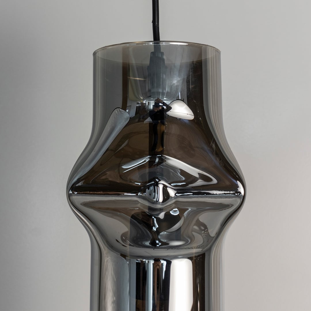 Closeup of chrome pendant light displaying smooth reflective surface and modern industrial-inspired structure.
