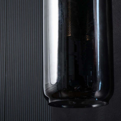 Detailed view of cylindrical smoked glass shade texture of modern wall light reflecting surrounding interior for elegant visual appeal.