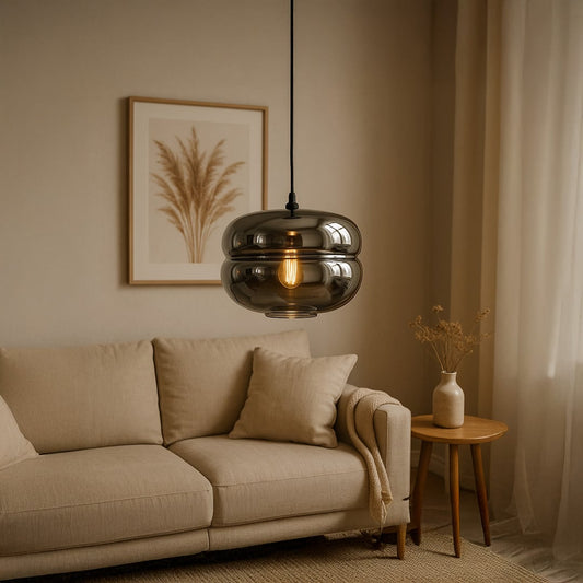 Modern smoked glass pendant light with warm glowing bulb hanging above a beige sofa creating a cozy elegant ambience in a neutral living room setting.