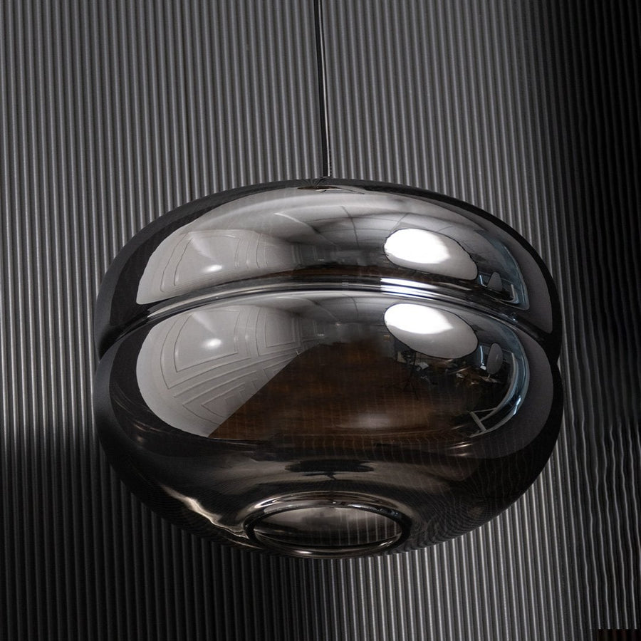 Smoked glass globe pendant light shown with light off on a dark backdrop highlighting its bold reflective design and modern curves.