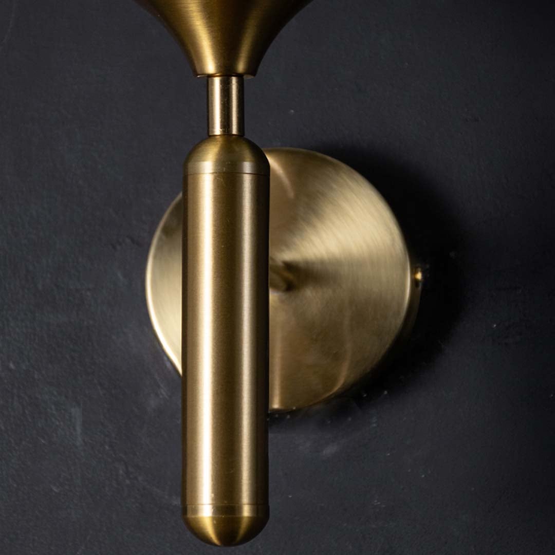 Detailed closeup of gold and black glass wall light highlighting its smoked glass globe and smooth metal accents for refined contemporary home decor.