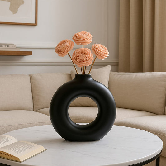 Peach sola flower arrangement displayed in a modern black round vase on a marble coffee table.