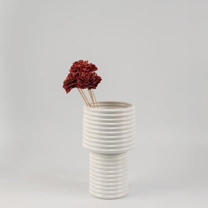 Red sola flower sticks arranged in a modern ceramic vase with artificial decorative flowers for stylish home and office decor.