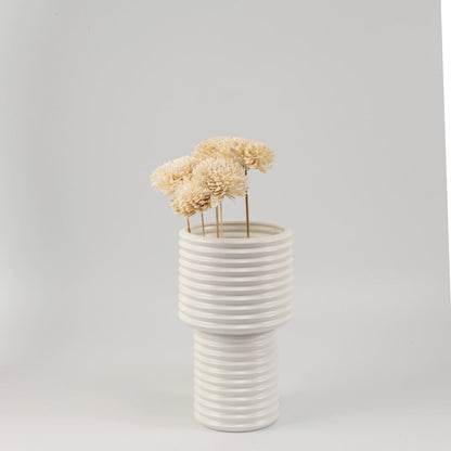 Cream sola flower sticks in a ribbed ceramic vase with artificial decorative flowers for modern home and office decor.
