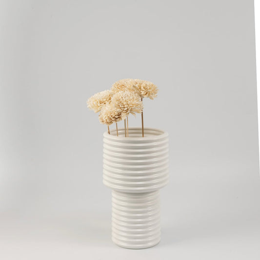 Cream sola flower sticks in a ribbed ceramic vase with artificial decorative flowers for modern home and office decor.