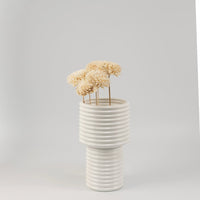 Cream sola flower sticks in a ribbed ceramic vase with artificial decorative flowers for modern home and office decor.