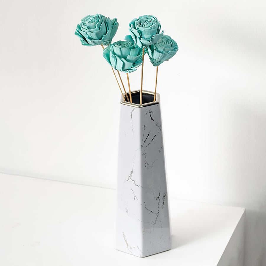 Blue dried flowers with natural stems in a white vase perfect for modern vase styling and home decoration.