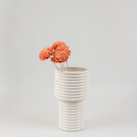 White ceramic ribbed vase styled with orange dried flower stems modern home decor accent for living room table.