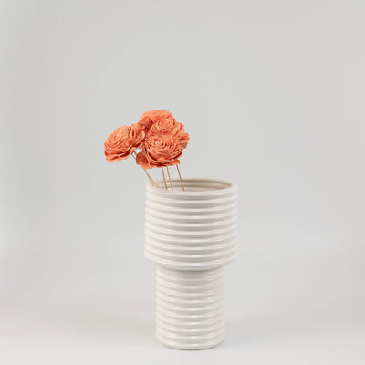 White ceramic ribbed vase styled with orange dried flower stems modern home decor accent for living room table.