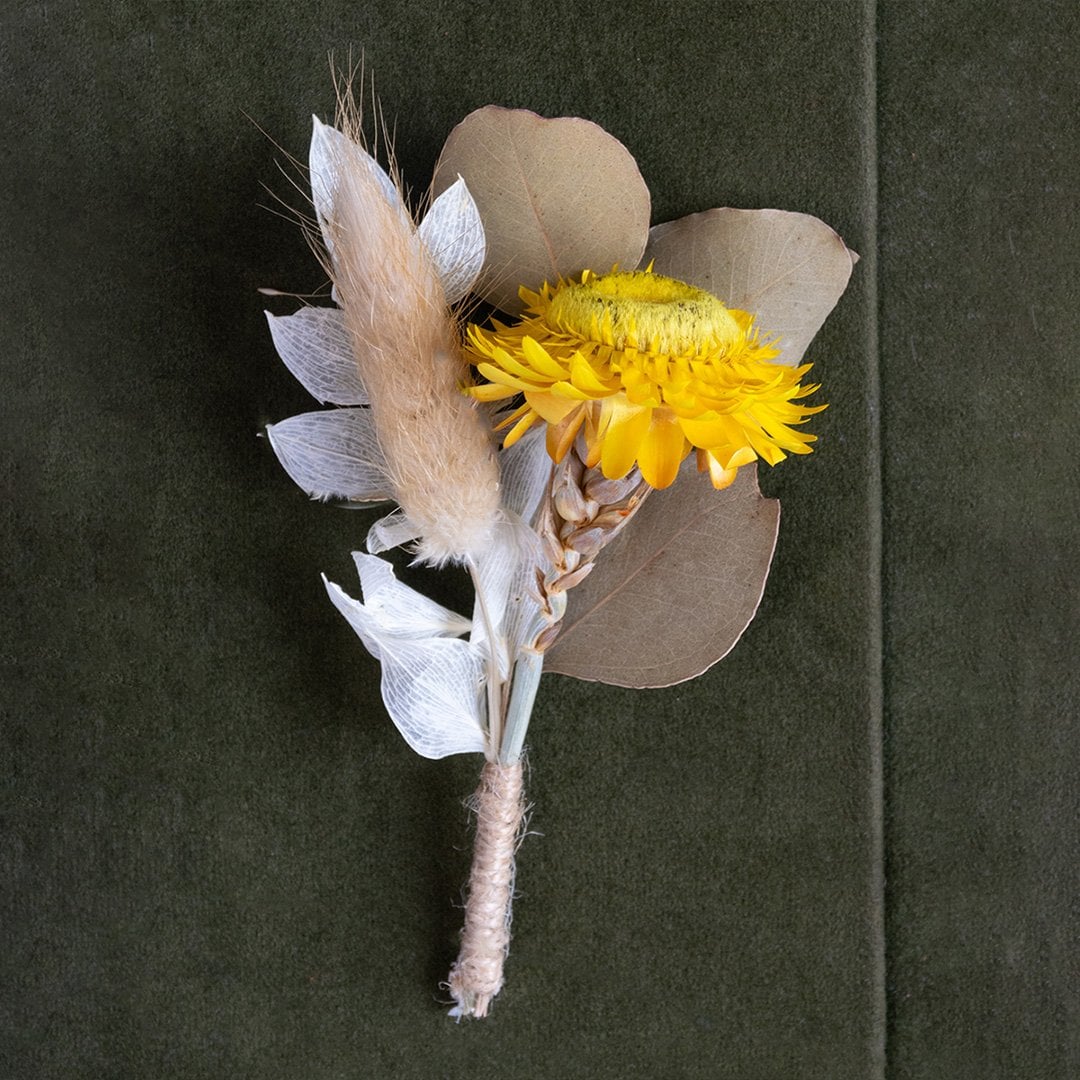 Closeup of preserved yellow flower bouquet with dried leaves and grass – decorative artificial flower arrangement.