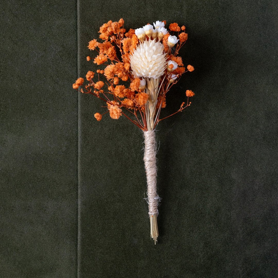 Closeup of dried flower bouquet with orange and white preserved blooms wrapped in jute – rustic artificial flower arrangement.