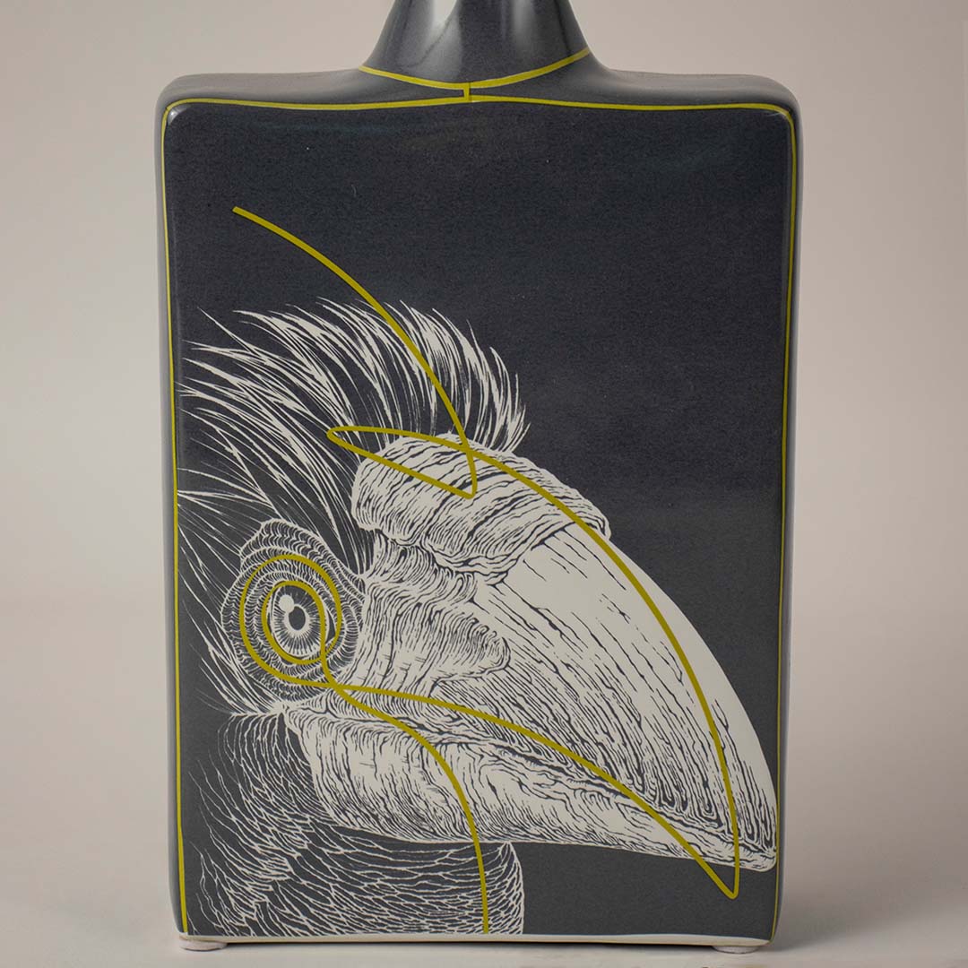 Decorative ceramic vase with bird illustration and dark finish placed on white surface against neutral background showcasing elegant artistic home decor statement piece.