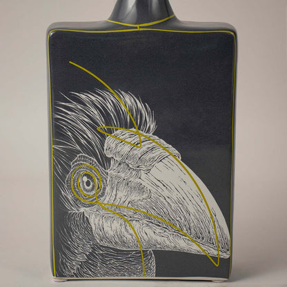 Decorative ceramic vase with bird illustration and dark finish placed on white surface against neutral background showcasing elegant artistic home decor statement piece.