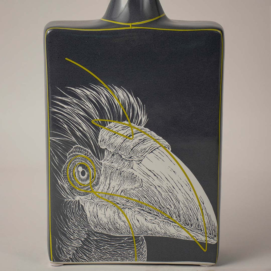 Decorative ceramic vase with bird illustration and dark finish placed on white surface against neutral background showcasing elegant artistic home decor statement piece.