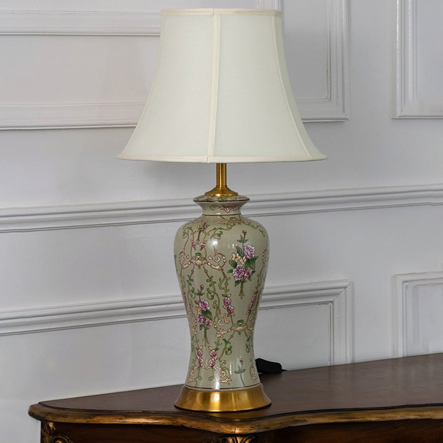 Classic ceramic lamp with hand painted floral motifs and golden base displayed with light off against white background.