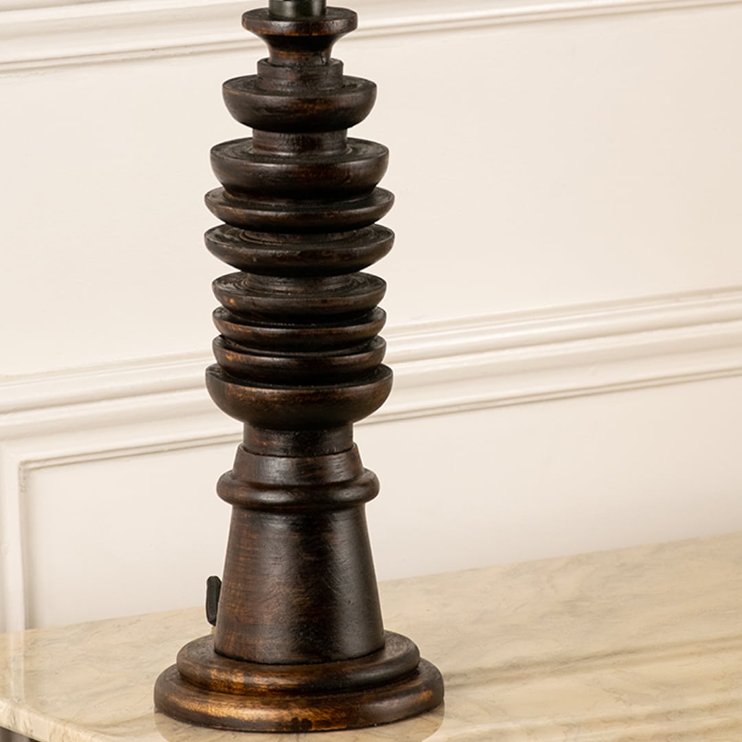 Turned wood lamp base with rich dark finish and bronze accents showcasing timeless craftsmanship and decorative appeal.