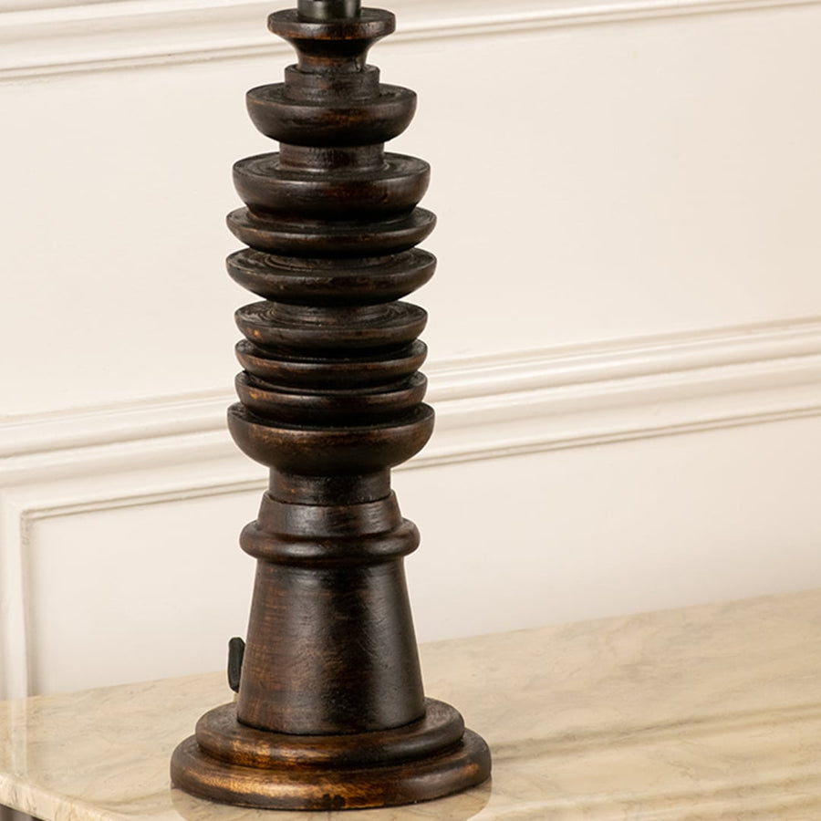 Turned wood lamp base with rich dark finish and bronze accents showcasing timeless craftsmanship and decorative appeal.
