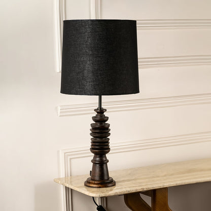 Black fabric shade table lamp with turned wood base and bronze accents for timeless interior decor styling.
