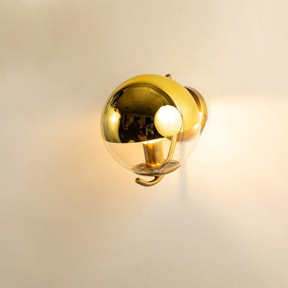 A gold metal and glass wall light shining warmly on a smooth white background creating gentle ambient illumination and adding luxurious modern décor.