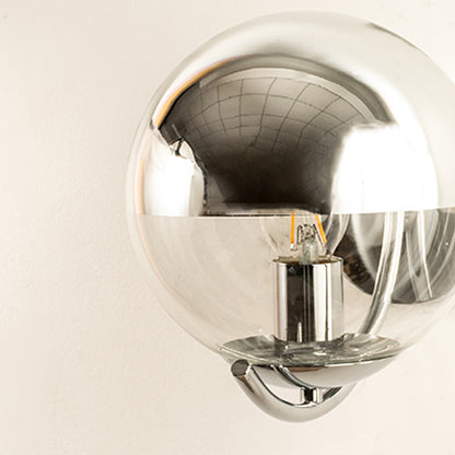 Closeup of chrome wall light with reflective globe shade showcasing mirror finish and modern design for interior wall decor styling.
