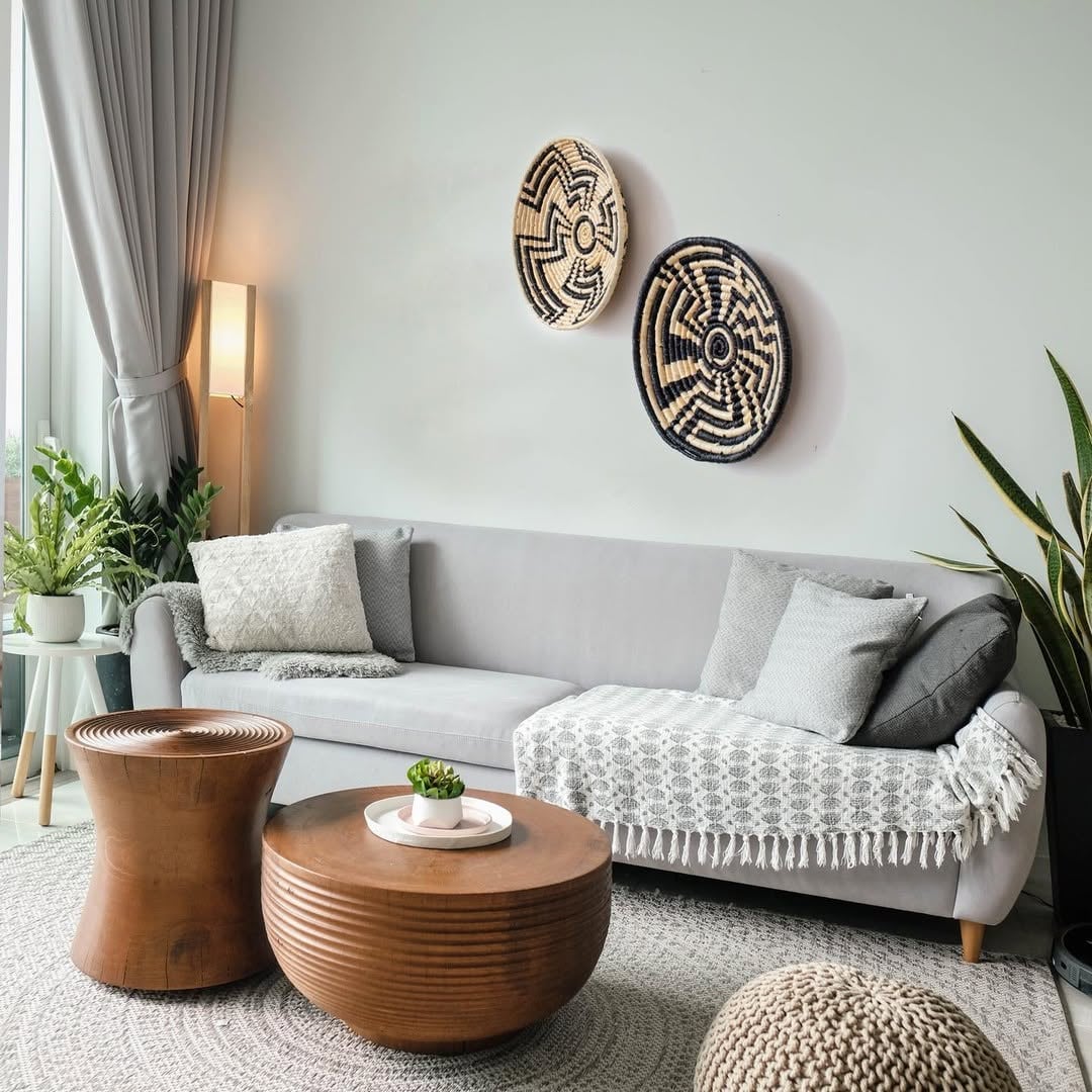 A handwoven black and natural rattan wall basket decor plate styled in a modern living room with a grey sofa wooden tables and indoor plants creating warm home decor vibes.