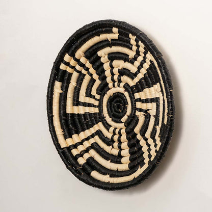 Side profile of the flat woven wall basket showing the thick natural fiber coils and black wrapping details on a white surface.