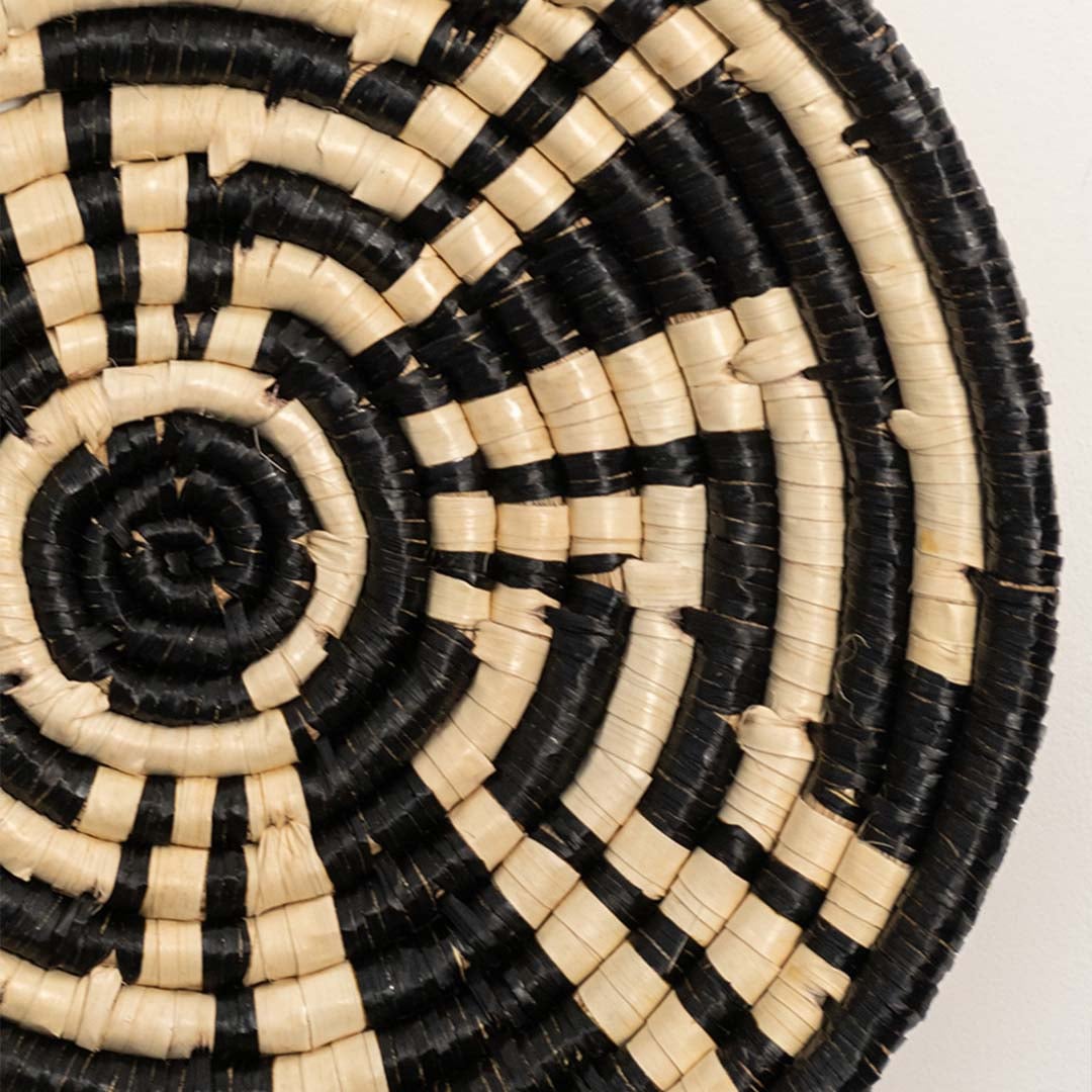 Detailed closeup view of the tight coil weaving and black wrapped sections on the natural seagrass wall basket surface quality.