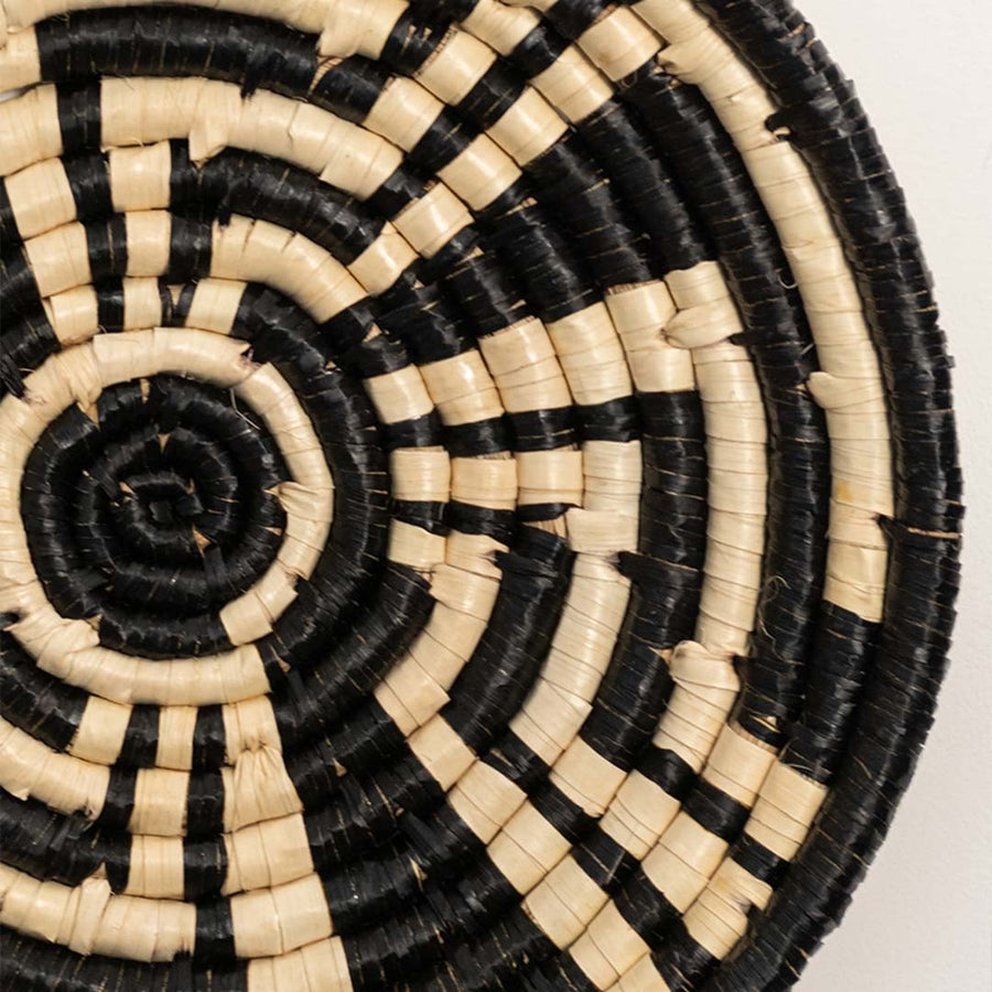 Detailed closeup view of the tight coil weaving and black wrapped sections on the natural seagrass wall basket surface quality.