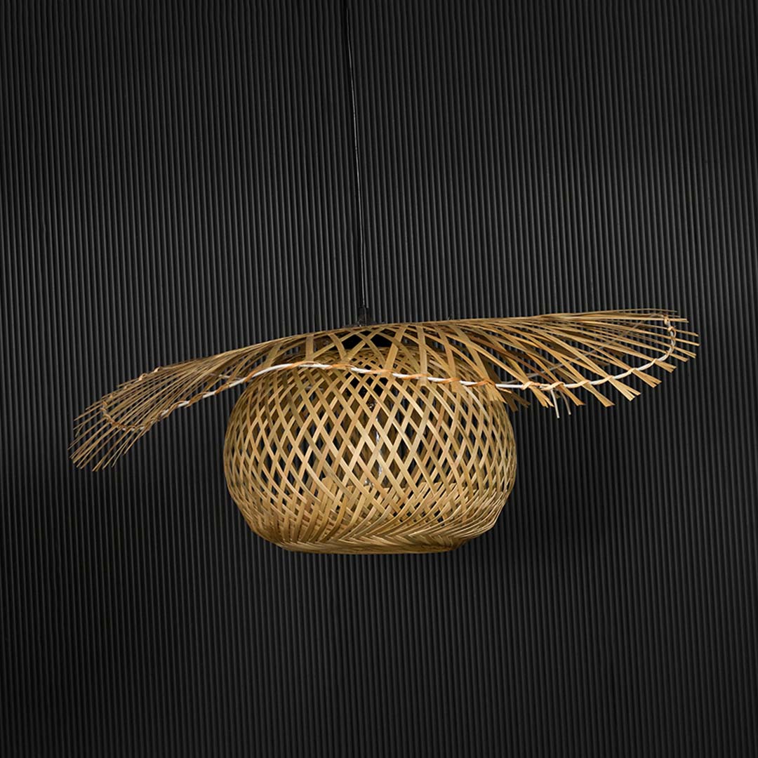 Rattan pendant light with wide handwoven bamboo shade in natural finish turned off against black background.