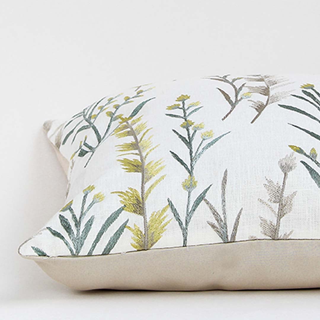 Soft cotton cushion cover with green floral embroidery shown at an angle offering a calm nature inspired décor accent with a breathable gentle and skin friendly fabric suitable for modern home styling.