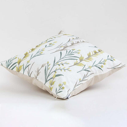 Soft cotton cushion cover with green and yellow botanical embroidery shown at an angle providing a fresh nature inspired décor accent with a breathable gentle fabric finish.