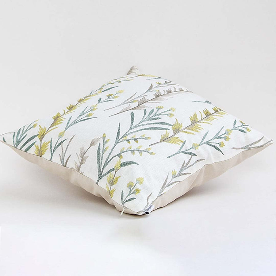 Soft cotton cushion cover with green and yellow botanical embroidery shown at an angle providing a fresh nature inspired décor accent with a breathable gentle fabric finish.