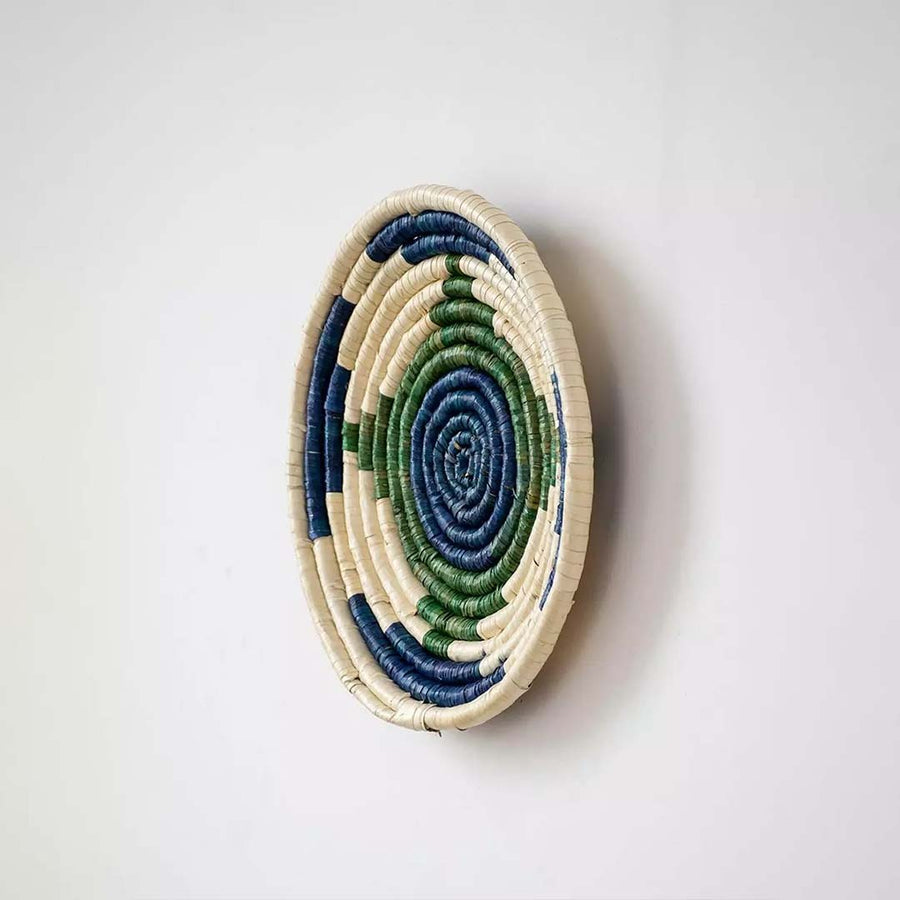 Side angle view of blue green wall basket highlighting its handcrafted depth weave texture and round shape.