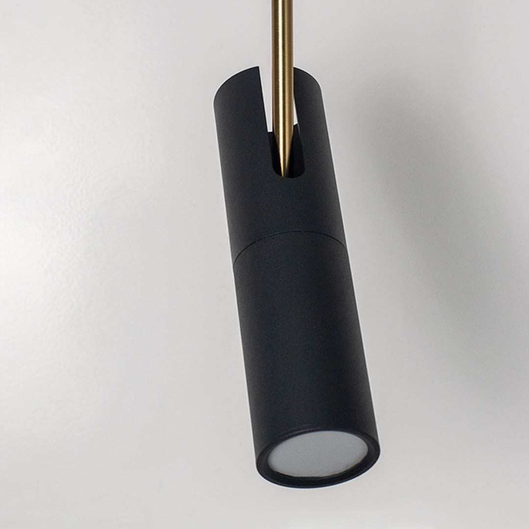 Closeup of modern black cylindrical pendant light with golden accent sleek ceiling lamp for luxury living and dining interiors.